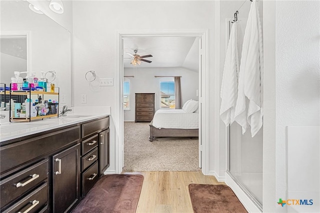 ensuite bathroom with wood finished floors, ceiling fan, a shower stall, vanity, and ensuite bath