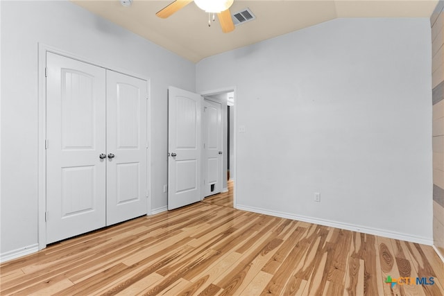 unfurnished bedroom featuring lofted ceiling, light wood-type flooring, ceiling fan, and a closet