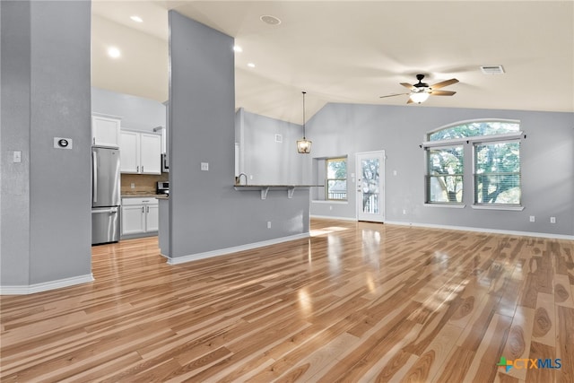 unfurnished living room featuring light hardwood / wood-style flooring, high vaulted ceiling, and ceiling fan