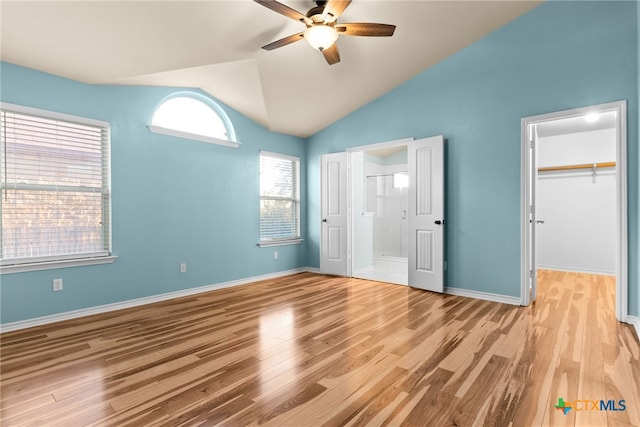 unfurnished bedroom with ceiling fan, lofted ceiling, a spacious closet, and light hardwood / wood-style flooring