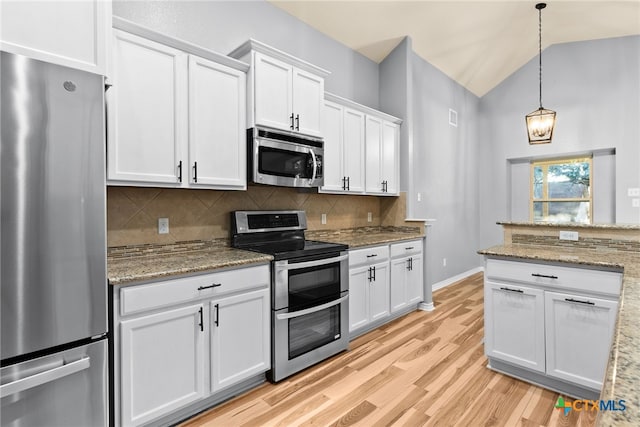 kitchen featuring decorative light fixtures, vaulted ceiling, appliances with stainless steel finishes, decorative backsplash, and white cabinets