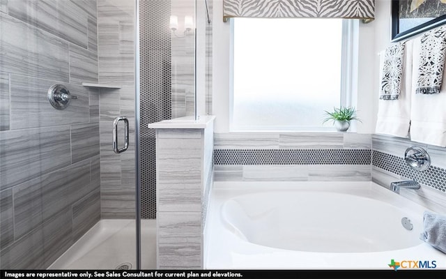 bathroom featuring a bath, a healthy amount of sunlight, and a shower stall