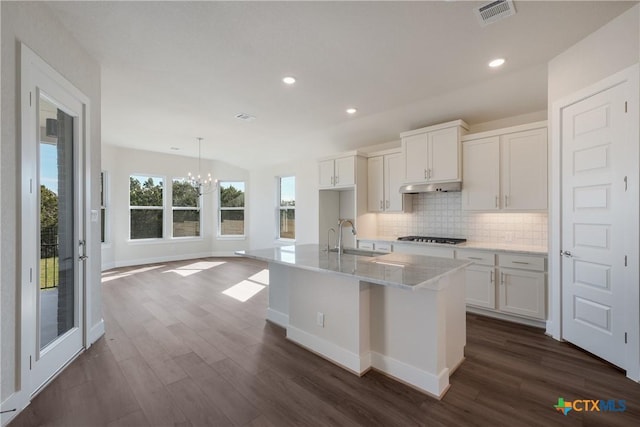 kitchen featuring pendant lighting, white cabinetry, sink, and an island with sink