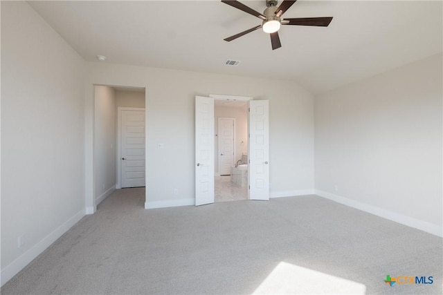 unfurnished bedroom featuring ceiling fan, light carpet, connected bathroom, and vaulted ceiling