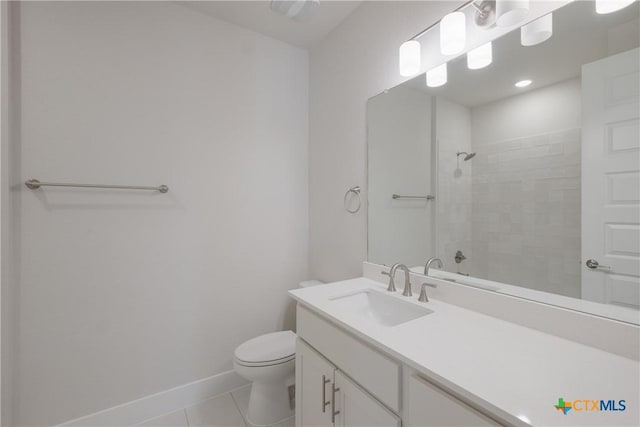 bathroom featuring tile patterned flooring, toilet, a tile shower, and vanity