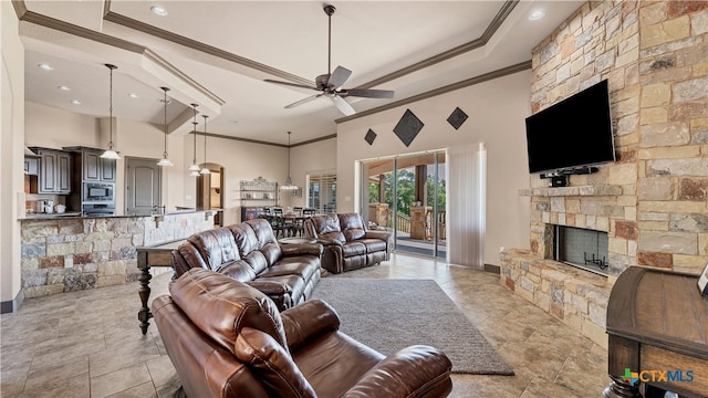 living room featuring a towering ceiling, a fireplace, ceiling fan, and crown molding