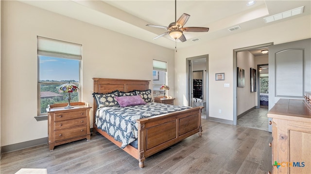 bedroom with hardwood / wood-style flooring, ceiling fan, multiple windows, and ensuite bathroom