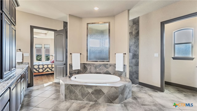 bathroom featuring tile patterned flooring, vanity, and tiled tub