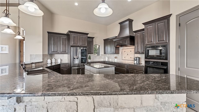 kitchen with black appliances, decorative light fixtures, sink, and custom range hood