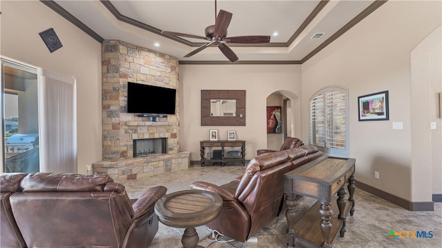 living room with a stone fireplace, plenty of natural light, ceiling fan, and crown molding