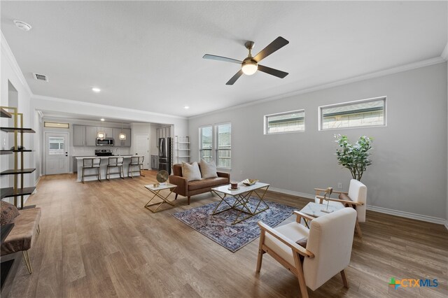 living room with light wood finished floors, visible vents, and baseboards