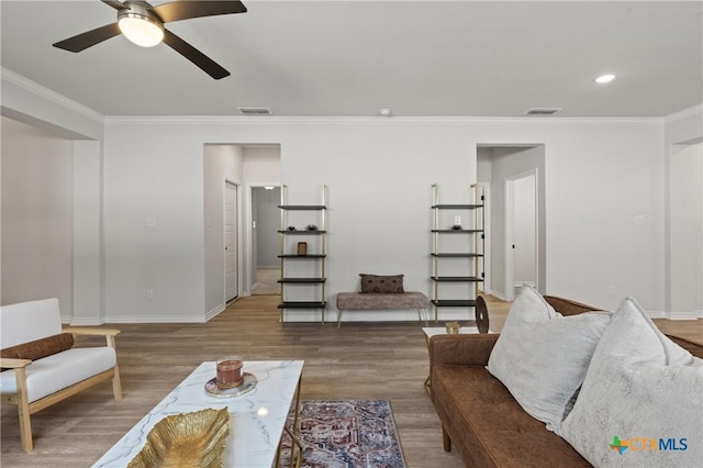 living area featuring ceiling fan, wood finished floors, visible vents, baseboards, and ornamental molding