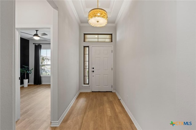 foyer entrance featuring baseboards, crown molding, and light wood finished floors