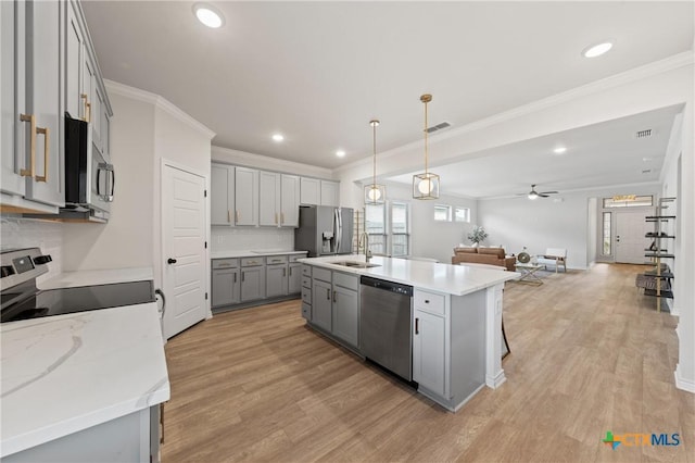 kitchen featuring gray cabinetry, stainless steel appliances, a sink, open floor plan, and light wood finished floors