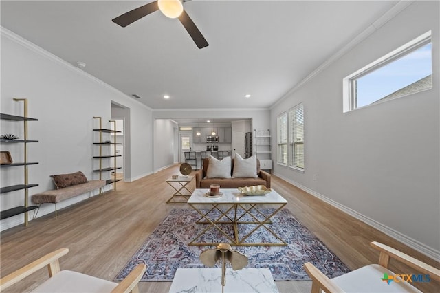 living room with baseboards, light wood-style floors, visible vents, and crown molding