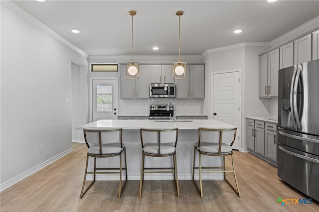 kitchen featuring appliances with stainless steel finishes, light wood-style floors, gray cabinetry, and a kitchen bar