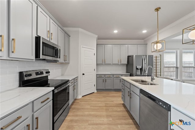 kitchen featuring crown molding, stainless steel appliances, gray cabinets, light wood-style floors, and a sink