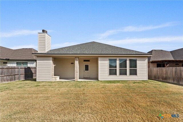 rear view of house with a patio area, a fenced backyard, a yard, and a chimney