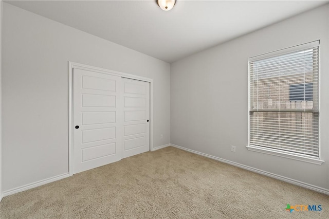 unfurnished bedroom with a closet, multiple windows, and carpet flooring