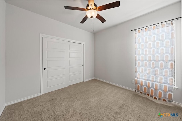 unfurnished bedroom with carpet floors, a closet, baseboards, and a ceiling fan