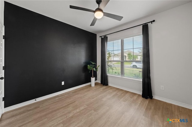 unfurnished room with light wood-style floors, baseboards, and a ceiling fan