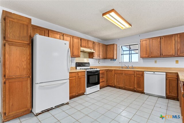 kitchen with a textured ceiling, white appliances, sink, and light tile patterned floors