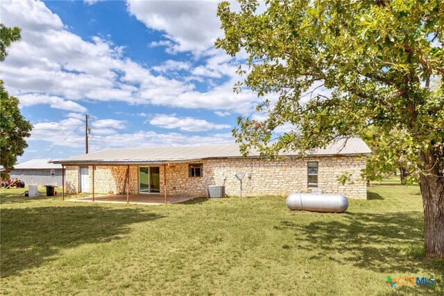 back of house with central air condition unit, a patio, and a yard