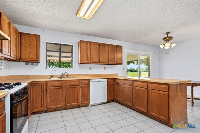 kitchen with kitchen peninsula, white appliances, sink, and a textured ceiling