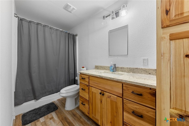 full bathroom featuring shower / bath combo with shower curtain, wood-type flooring, vanity, and toilet