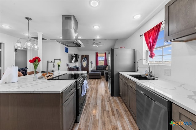 kitchen featuring stainless steel appliances, sink, ventilation hood, light hardwood / wood-style flooring, and decorative light fixtures