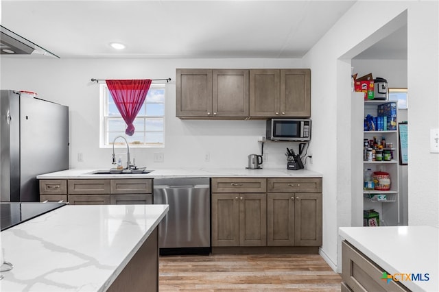 kitchen featuring light hardwood / wood-style flooring, sink, light stone counters, and stainless steel appliances