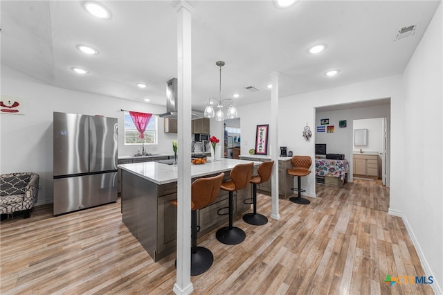 kitchen featuring stainless steel refrigerator, pendant lighting, a kitchen breakfast bar, light hardwood / wood-style floors, and a center island