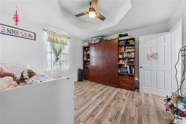 interior space with ceiling fan, a tray ceiling, and light hardwood / wood-style floors