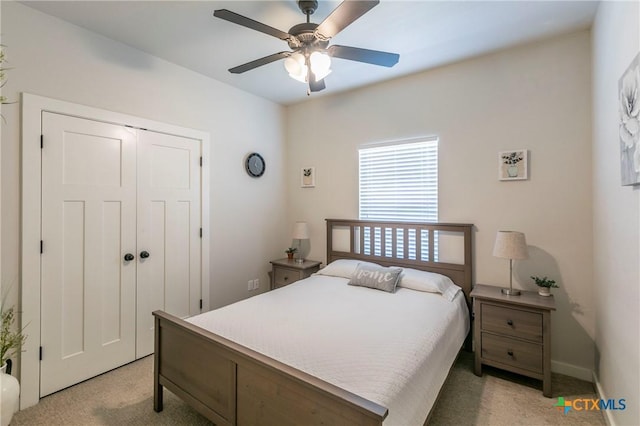 bedroom featuring a ceiling fan, a closet, light colored carpet, and baseboards