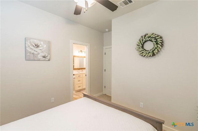 bedroom with ceiling fan, connected bathroom, a sink, visible vents, and baseboards