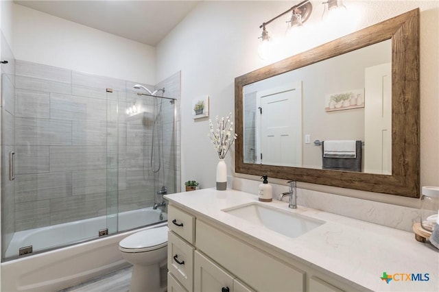 full bathroom featuring combined bath / shower with glass door, vanity, and toilet