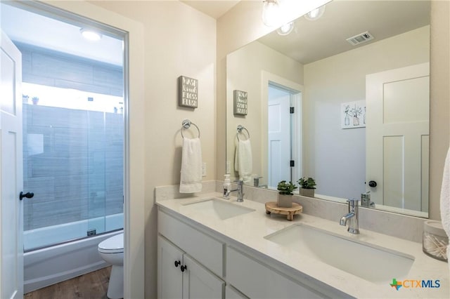 full bathroom featuring toilet, double vanity, a sink, and visible vents