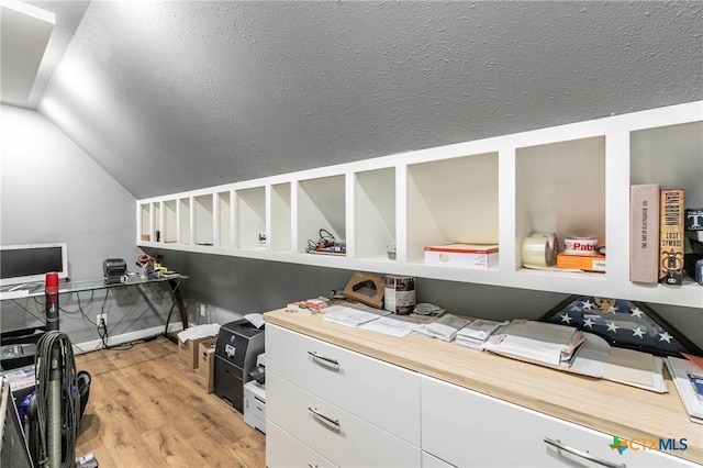 office space featuring lofted ceiling, light wood-style floors, and a textured ceiling