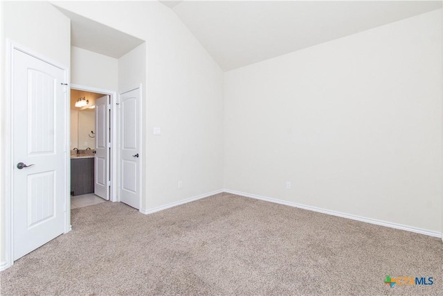 carpeted empty room featuring vaulted ceiling