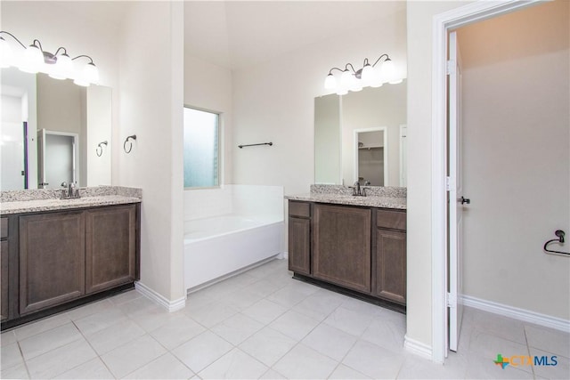 bathroom with tile patterned flooring, a bathtub, and vanity