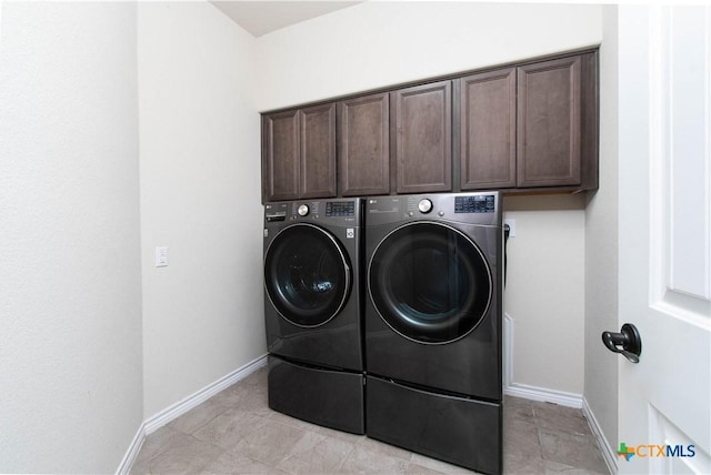 washroom featuring washing machine and clothes dryer, light tile patterned floors, and cabinets