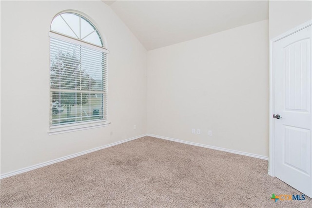 carpeted spare room with vaulted ceiling