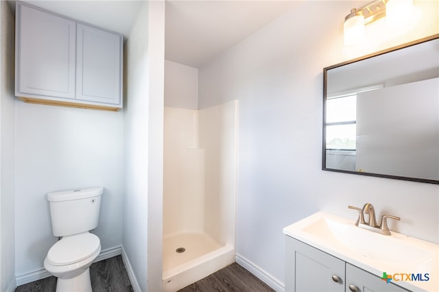 bathroom with a shower, hardwood / wood-style flooring, vanity, and toilet