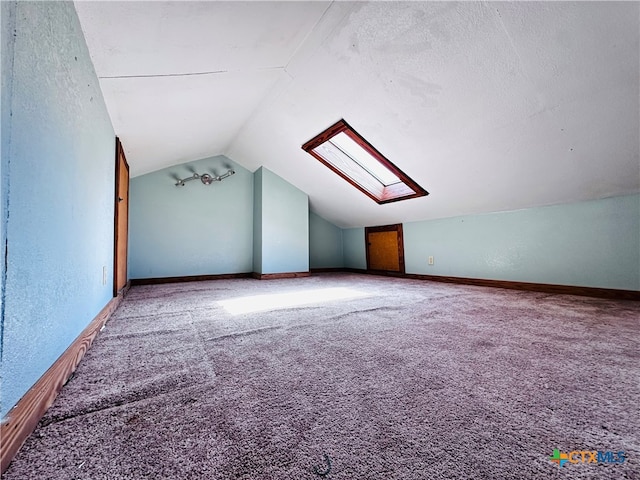 additional living space with vaulted ceiling with skylight, a textured ceiling, and carpet flooring