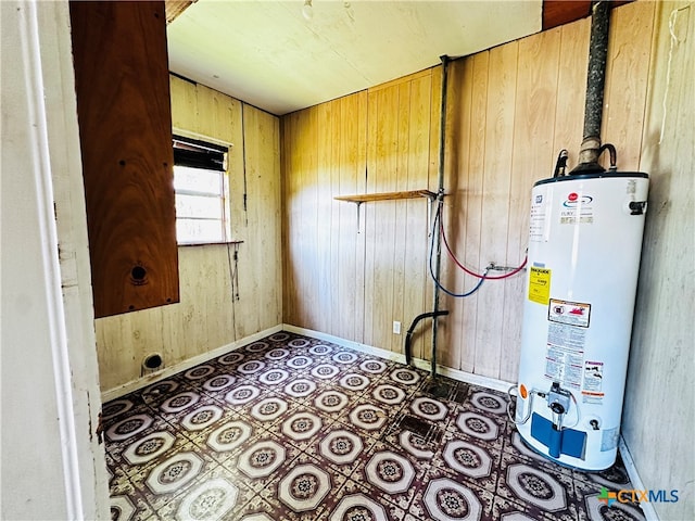 laundry room featuring water heater and wood walls