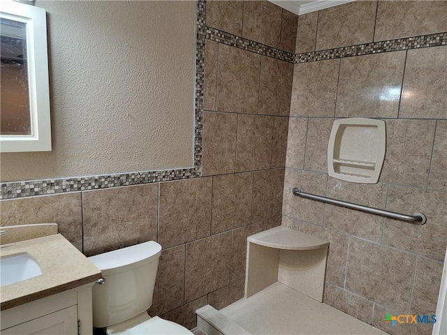 bathroom with vanity, toilet, and tile walls