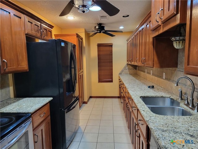 kitchen with light stone countertops, backsplash, a textured ceiling, sink, and light tile patterned flooring