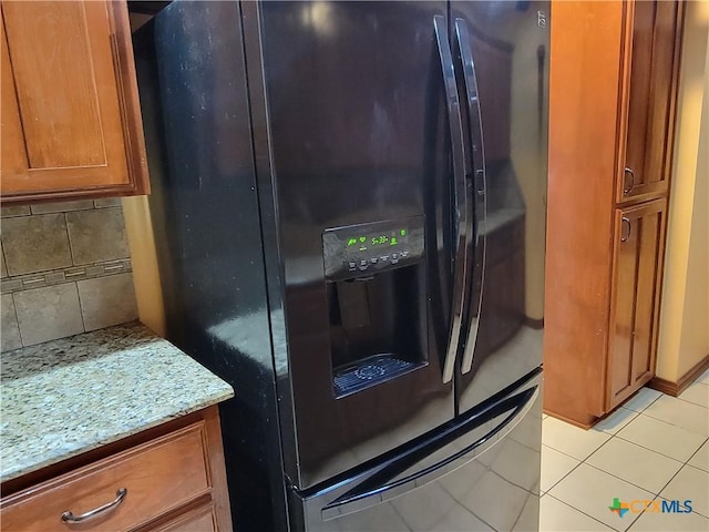 room details with backsplash, black refrigerator with ice dispenser, and light stone counters