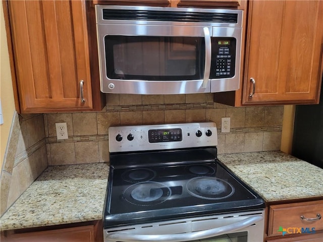 kitchen featuring stainless steel appliances, light stone counters, and tasteful backsplash