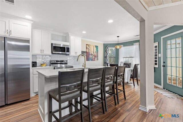 1301 Chapel Creek Rd, Waco, TX 76712 - kitchen featuring appliances with stainless steel finishes, a sink, light countertops, ornamental molding, and a kitchen breakfast bar